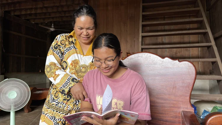 Leakna enjoys reading, having received her prescription eyeglasses. Photo: The Fred Hollows Foundation