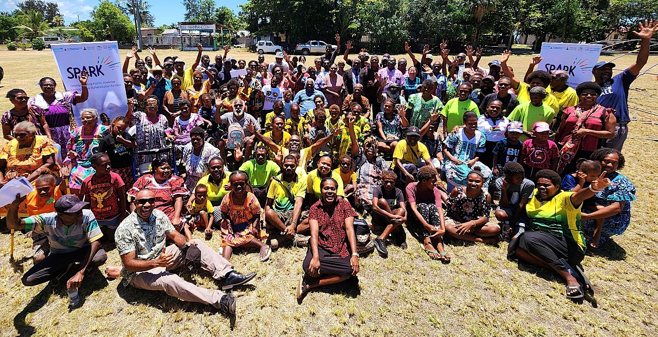 Attendees gather for a group photograph at the official launch event for the SPARK program in Micronesia. Participants pose on a sunlit field, framed by two banners highlighting the 'Stronger Pacific Alliance for Rehabilitation for Kids' initiative, marking the commencement of the programme