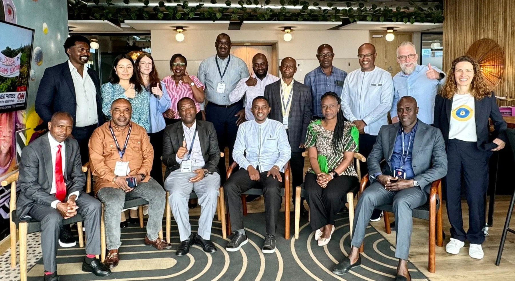 Group photo of diverse professionals gathered indoors, smiling and posing together at a meeting or workshop.