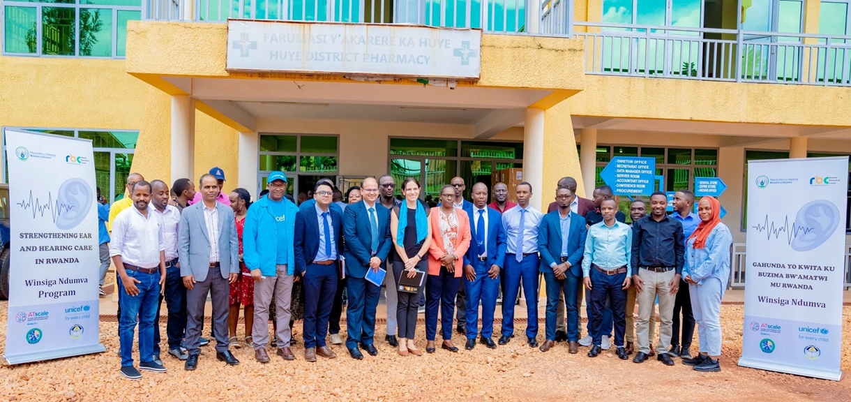 Group of partners and officials standing outside a district pharmacy in Rwanda at a hearing care programme launch