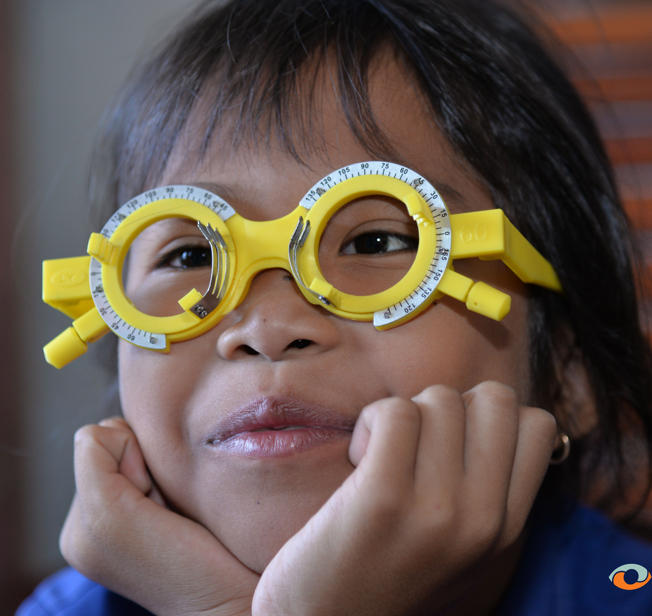 Close-up of a child wearing yellow trial frames during an eye examination
